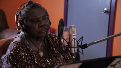 Yindjibarndi Elder Tootsie Daniel sits in a recording studio in front of a microphone with her eyes closed.